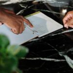 Hands pointing at menu on black marble counter inside a shop.
